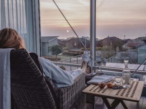 Kvinna i fåtölj på Torekov hotell spa med utsikt mot havet.