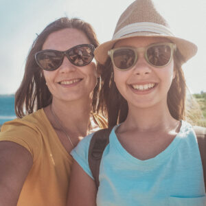 Selfie på mor och dotter i sommarsol och med havet i bakgrunden