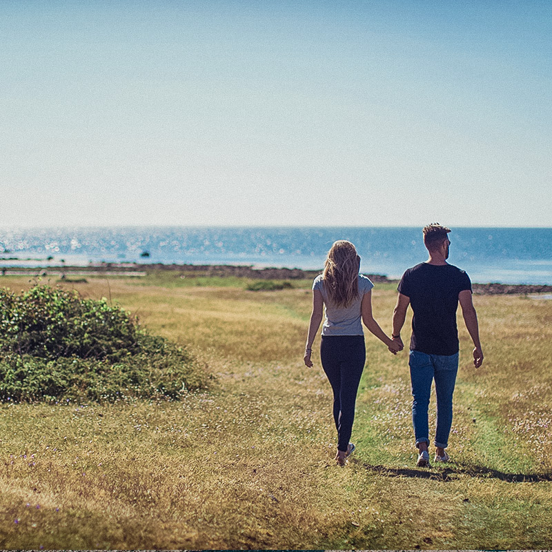 Par promenerar hand i hand vid havet